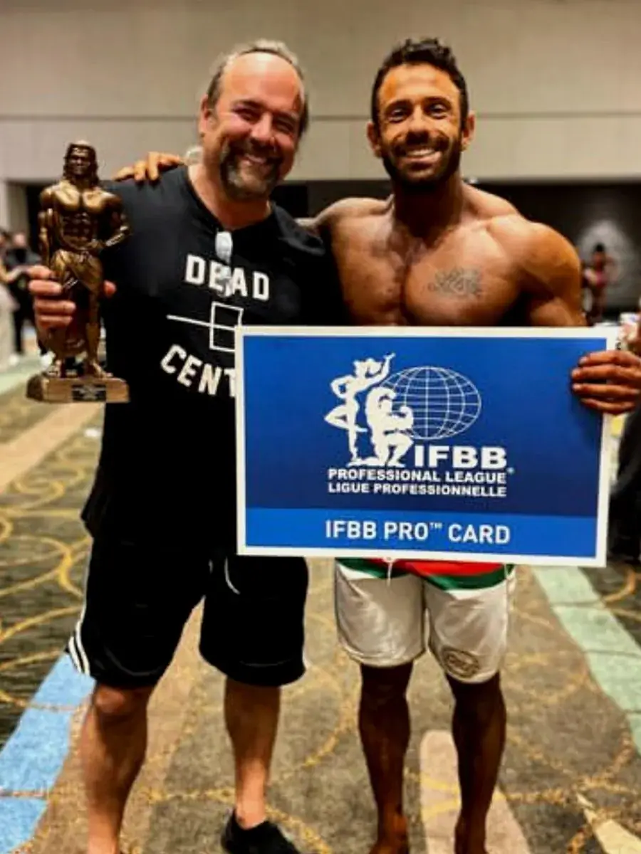 Steven Kushnir holding IFBB Pro card at NPC Nationals 2020